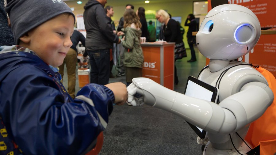 Kinder begrüßt Roboter mit der Faust