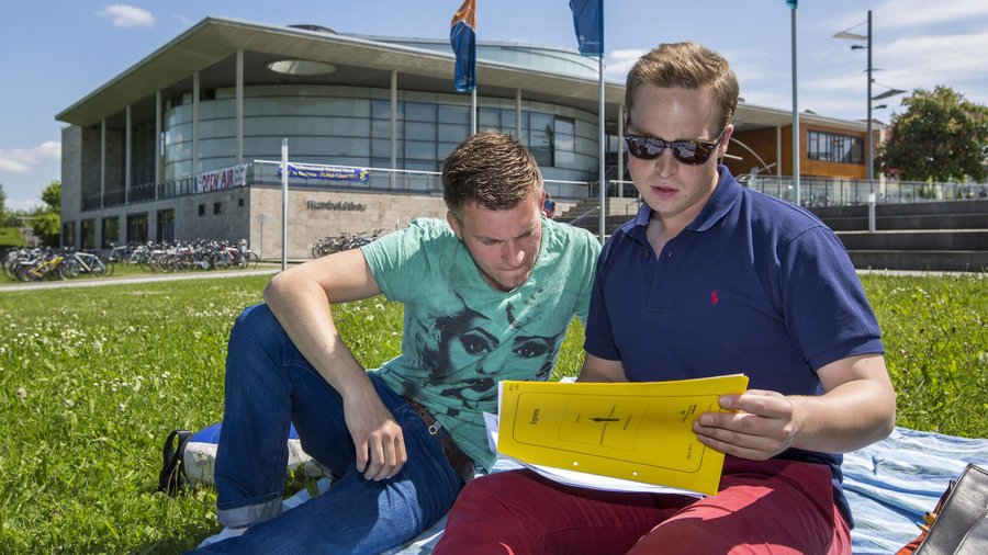 Studierende sitzen auf der Wiese vor dem Humoldtbau der TU Ilmenau