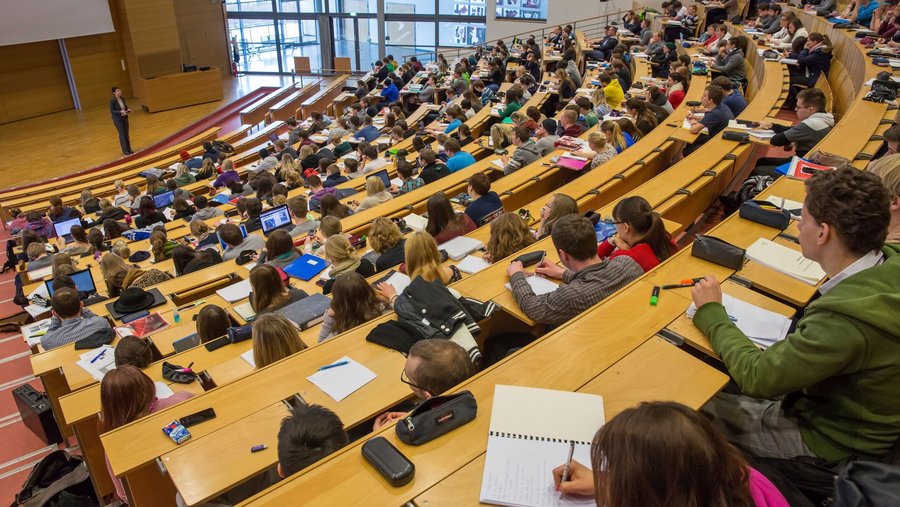 Studierende sitzen im vollen Hörsaal.