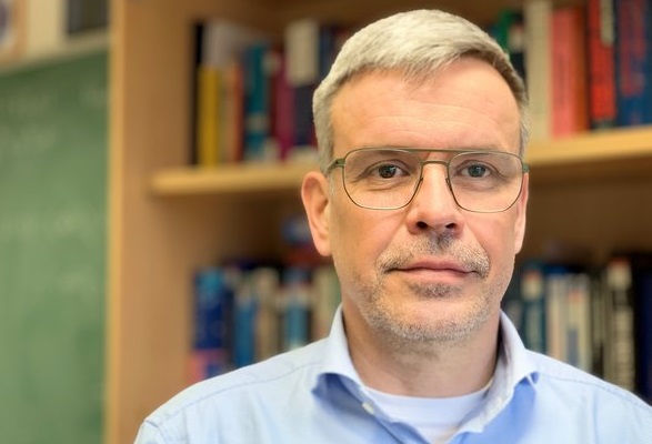 Prof. Jörg Schumacher vor Bücherregal