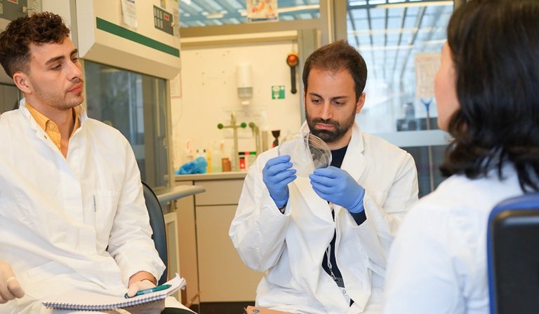 Personen mit Kittel und Handschuhen in einem Labor