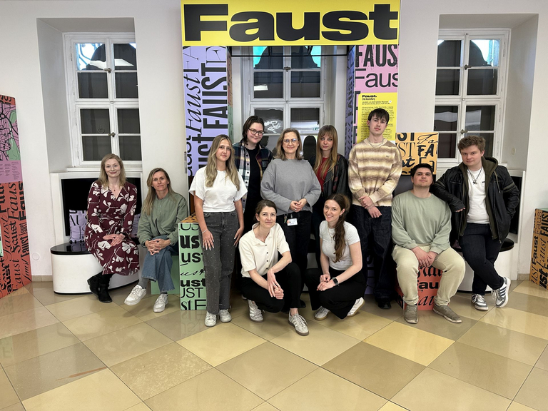 Personengruppe vor FAUST-Schild