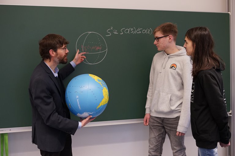 Three people in front of a black board